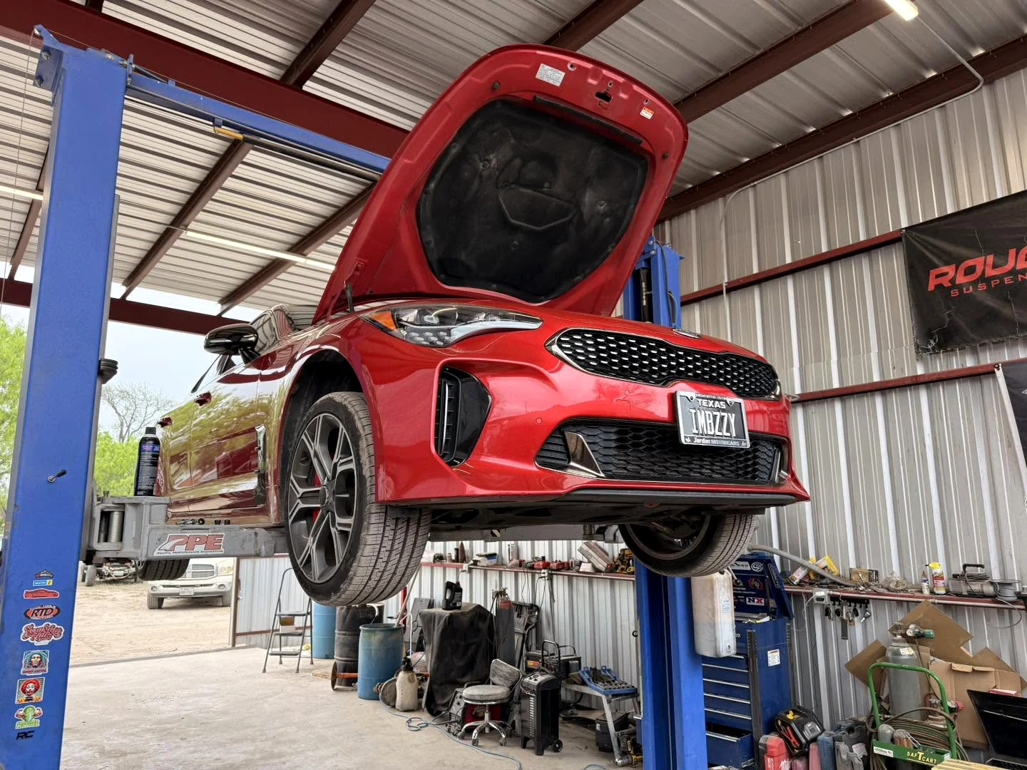 Red vehicle raised on a lift inside the Envy This Kustoms shop